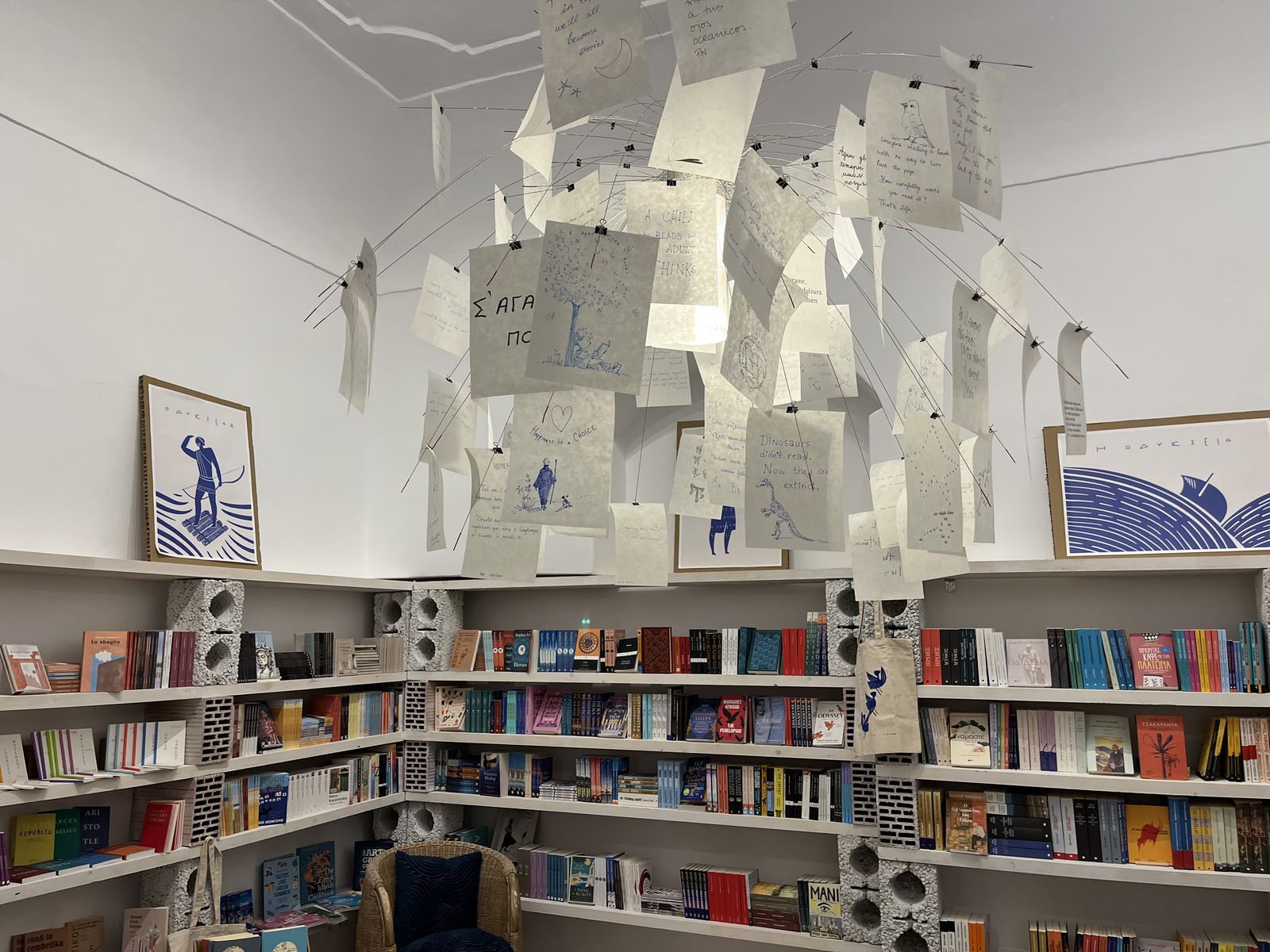 Inside Demodocos Books — handwritten poems hung from the ceiling above the shelves, beside blue prints